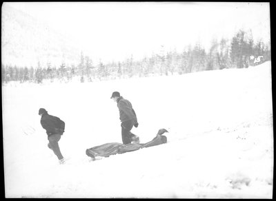 Two people are talking through the snow near what is presumably a body bag after an avalanche hit a train on the Northern Pacific Railroad. Three people died.