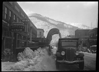 Photo of the snow loading truck that is actively removing snow outside of the Combination Grocery and Lunch shop in Wallace, Idaho.