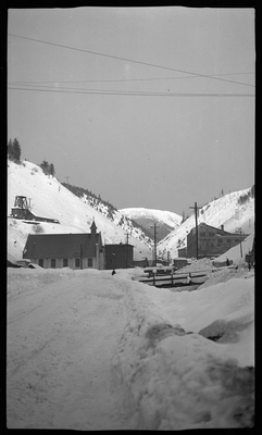 Photo of a snowy scene, with several buildings seen in the distance. One appears to be a church.