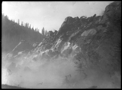 The aftermath of the blast. The dust has not yet settled, but large chunks of rock are visible.