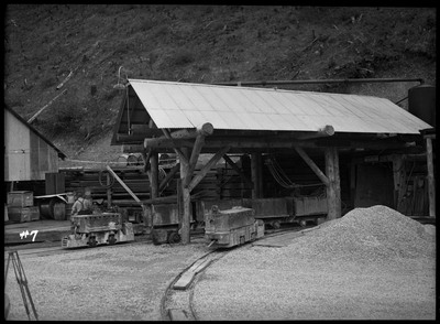 Image of the Silver Summit mine entrance. There are mine carts on tracks that leads into the mine.