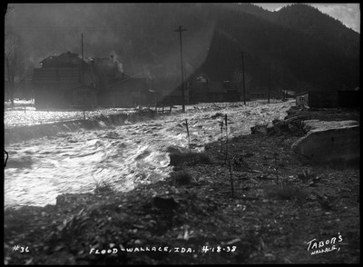 Flood in Wallace, Idaho where the water is rushing over the streets and through the creek. The creek is overfilled.