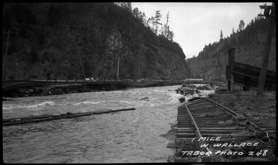 Flooding one mile from Wallace, Idaho. Structural and road damage can be seen on the sides.
