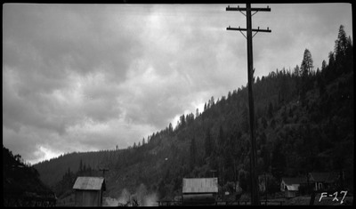 View of a hillside during the Placer Creek flood. A few buildings and telephone pole can be seen.