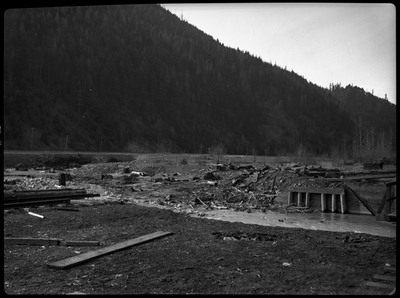 Landscape image of the damage caused of flooding. There is a complete break in the railroad tracks, now covered by debris.