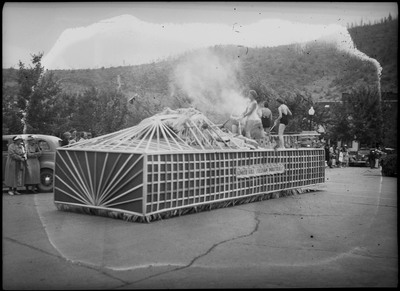 Women wearing swimsuits on the Bunker Hill and Sullivan Industries parade float while people watch.