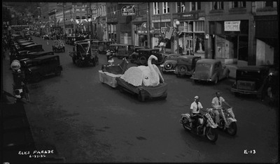 Two men on motorcycles, a woman on a swan float and several other vehicles during the Benevolent and Protective Order of Elks parade.