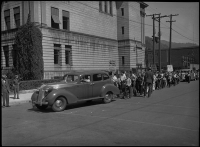 A vehicle rounding the corner and children walking behind the vehicle (some holding signs) during the back-to-school parade.