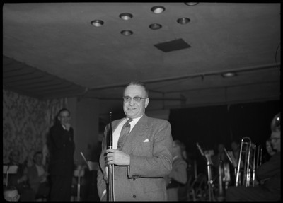 A man holding onto a microphone at March of Dimes event at the B.P.O.E. temple. A band can be seen in the background.