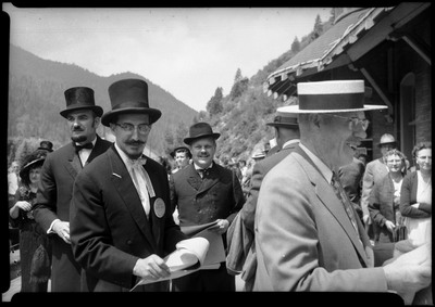 Men dressed in top hats during the Silver Jubilee fire derby event and art fair. Other people can be seen in the background.