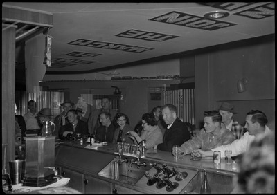 Image of the bar area and people standing behind the bar area during the Albie's March of Dimes event. There is decorative text on the ceiling.
