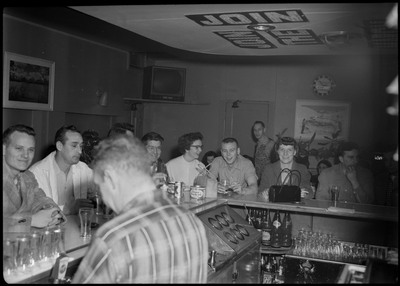 Image of the bar area and people standing behind the bar area during the Albie's March of Dimes event. There is decorative text on the ceiling.