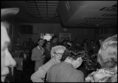 Scene during the Albie's March of Dimes event. People are sitting at the bar counter or standing or sitting at tables.