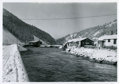 A river runs past several buildings during a flood in Wallace.