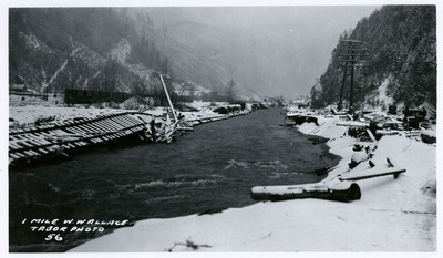 A section of local infrastructure appears to have fallen into a river following the Wallace flood. It's unclear if the materials were part of the bridge or the nearby road. Several vehicles and telephone poles are visible nearby.