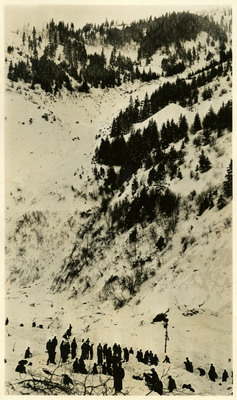 A group of people work to remove snow left by the Burke snowslide.