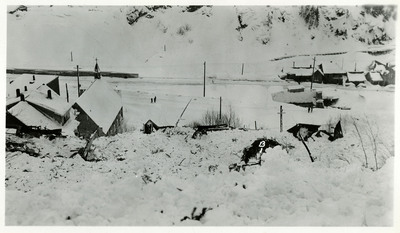 Snow and debris covers Burke following snowslide. A few people walk nearby.