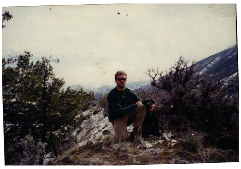 A photograph of a man and a dog on a mountain. It's labeled "Aaron Foster and Wyatt, Summer 95. Winter of 96."