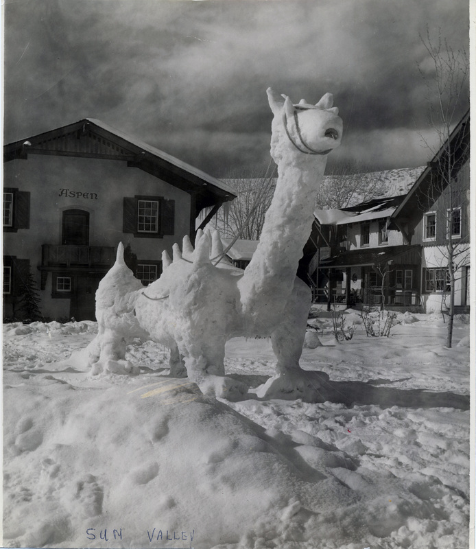 A large creature made of snow is in front of a building with the word "Aspen" on it. "Sun Valley" is written on the front of the photograph.