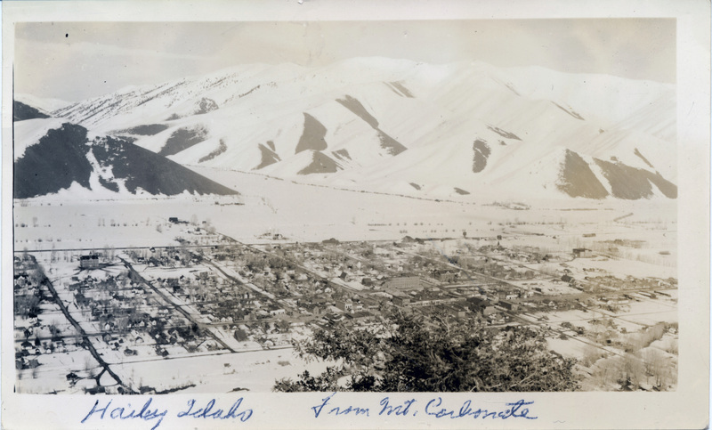 A view from above of a town at the base of a mountain range. "Hailey, Idaho from Mt. Carbonate" is written on the front of the photo.