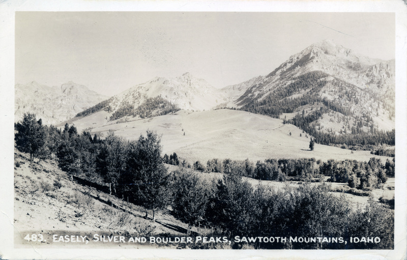 A postcard with a photo of mountains surrounding a meadow. "483. Easely, Silver, and Boulder Peaks, Sawtooth Mountains, Idaho" is printed on the bottom of the photo. The back of the postcard is blank.