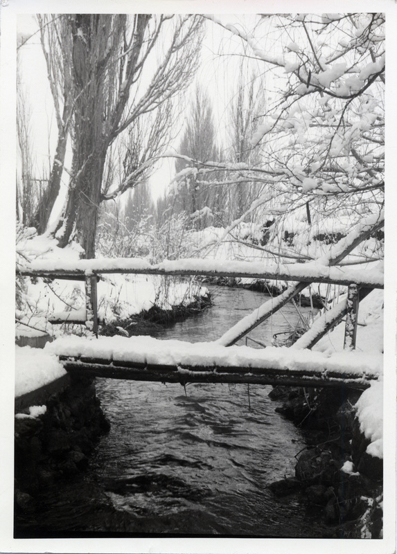 A snow-covered bridge over a creek.