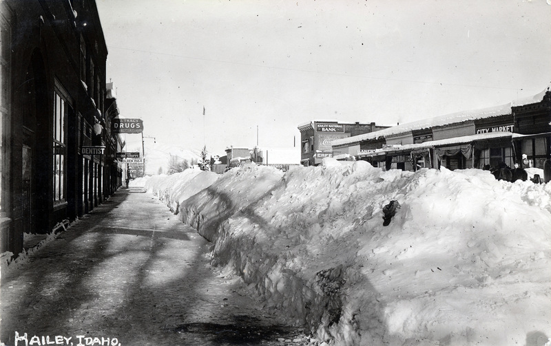 A postcard featuring a picture of a snow-covered downtown street after the sidewalk has been plowed. "Hailey, Idaho" is printed on the picture. The back of the postcard is blank.
