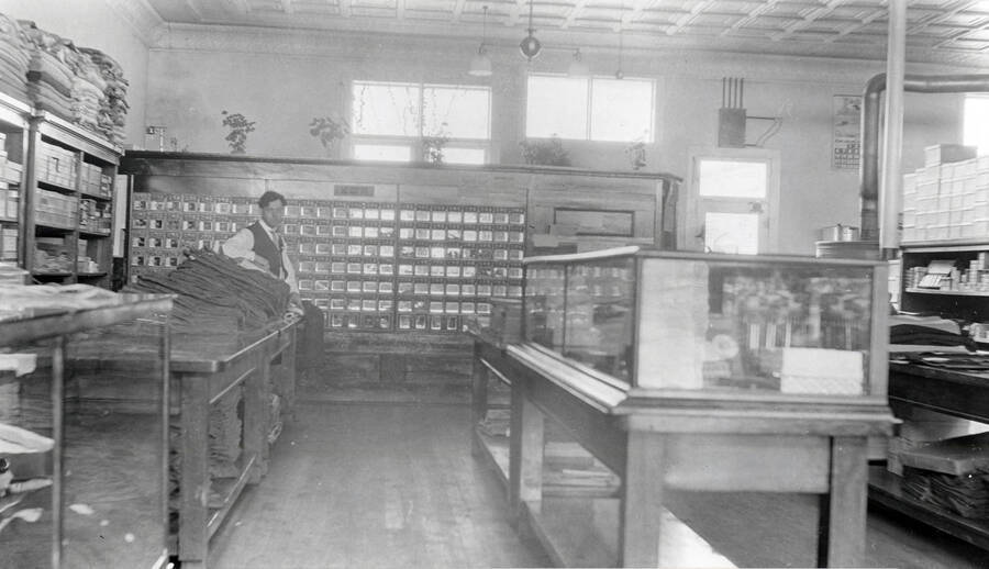 After reconstruction, the post office was placed inside the E.K. Parker store. Here it is, with Dan Featherstone, postmaster, and dry goods section of the store.