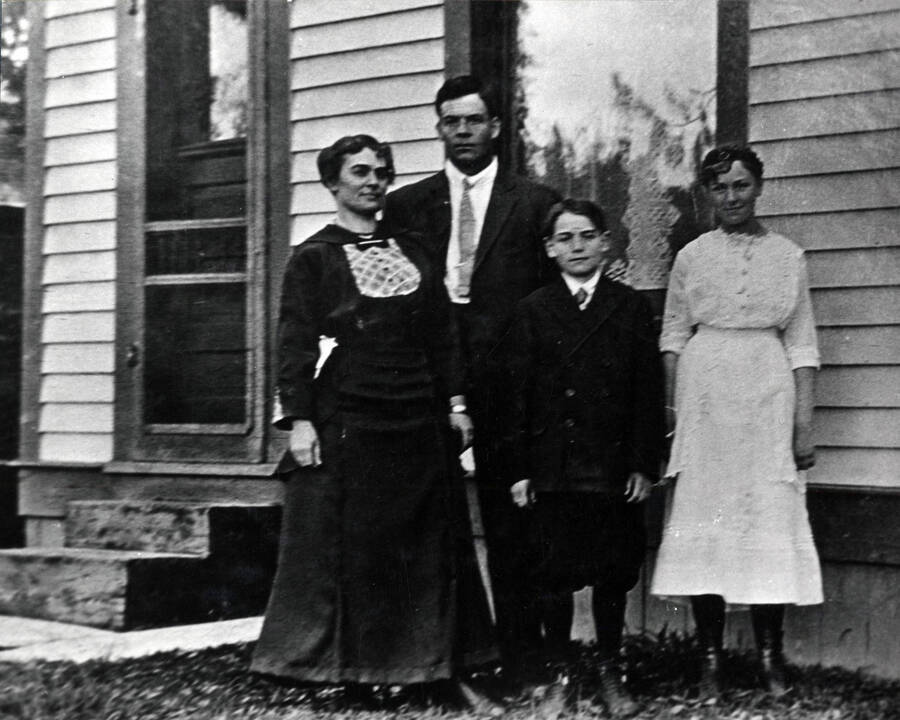 Pictured standing in front of a house, from left to right: Mrs. Bellows, Harley Bellows, Joe Evans, and Nora Evans.