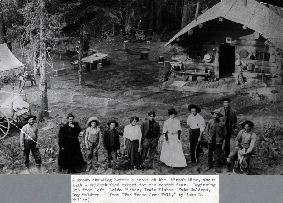 A group standing before a miner's cabin at the Mizpah Mine, about 1914. Left to right: four unidentified, Leila Fisher, Irwin Fisher, Kate Waldron, Ray Waldron, three unidentified. From 'Trees Grew Tall.'