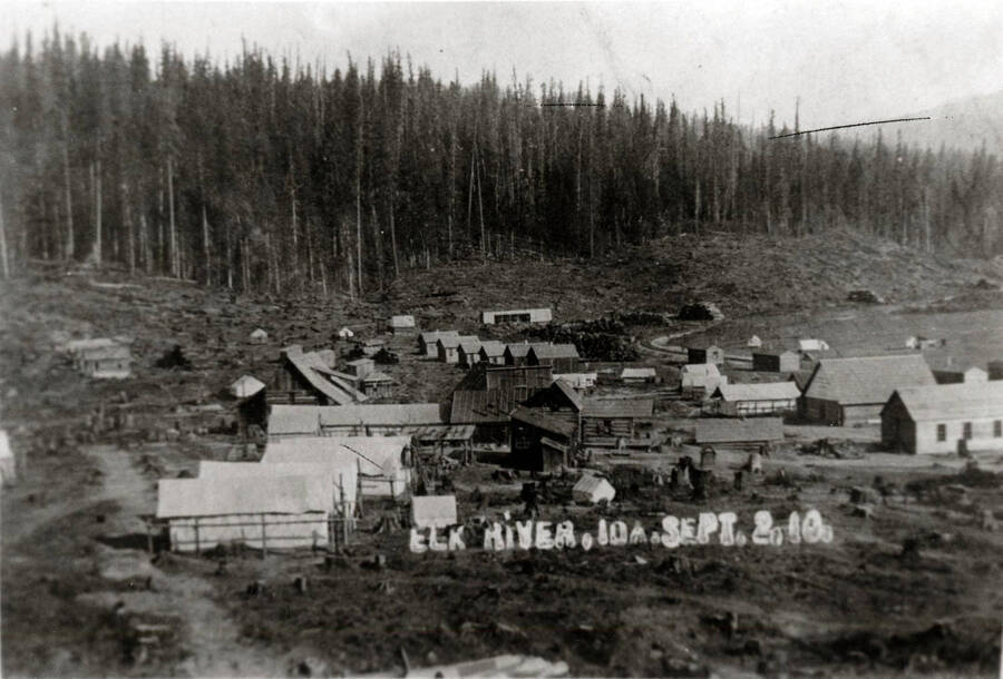 Book caption: 'This is how Elk River looked in September, 1910. Clustered at the center are the log buildings which include the Trumbull homestead  and (its roof visible over the homestead cabins) a store. In the Foreground are tents; toward the rear a line of Company houses; at the right, Potlatch Company Headquarters, the messhall, and the railroad.'