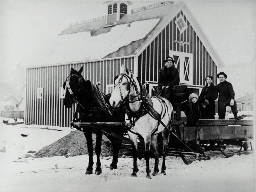 Sleigh, team, and riders in front of Harless Livery Stable, Bovill, Idaho. Left to right: John Donner, Lee Witty, Mrs. Harless, J. P. Harless.