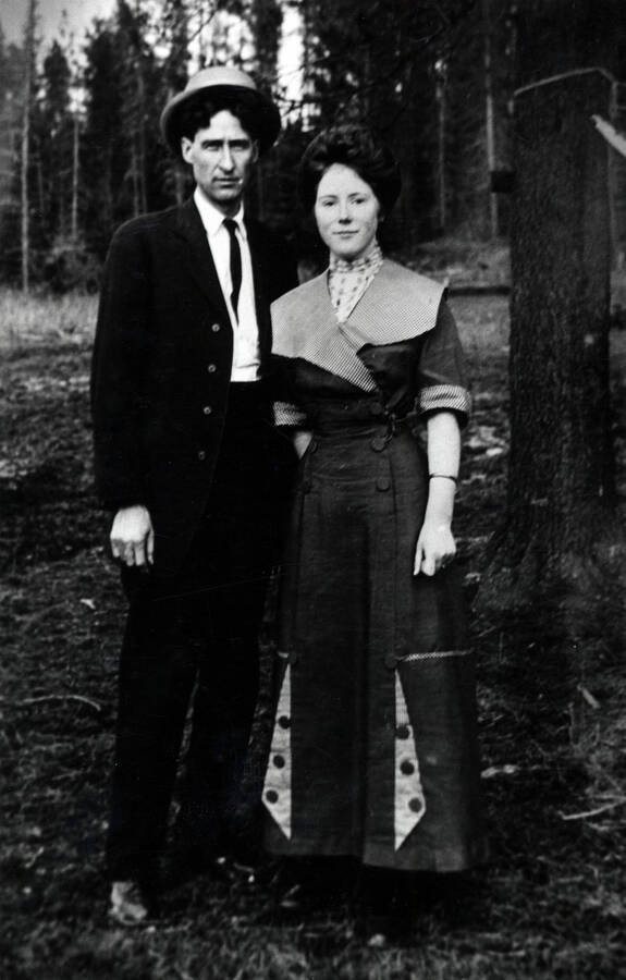 Ernie and Nell Smith are pictured standing together in front of a timber stand dressed in a suit and dress, respectively.