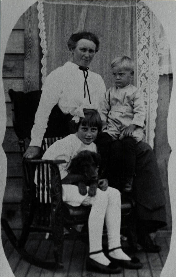 Minnie B. Miller with her children Luzella (seated in chair), John B. Miller, and dog, Keno, in front of their home.