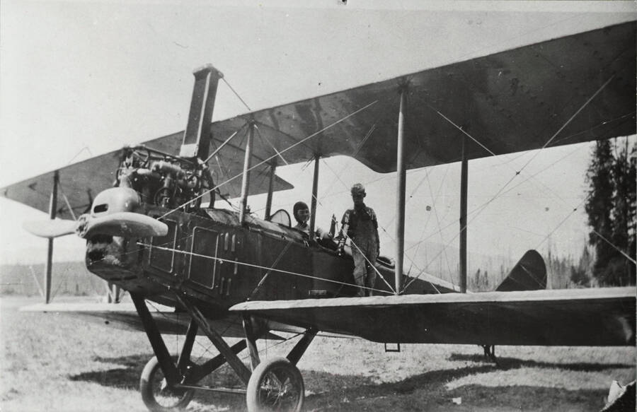 N.B. Mamer's airplane. John B. Miller standing on wing; Gladys Miller in passenger seat. [The biplane appears to be a Standard J-1, but may be an earlier model due to the exposed engine components.]