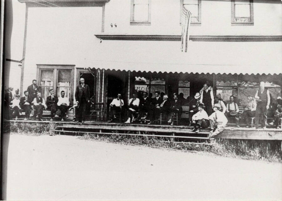 Located on the east side of Main Street. A large group of people are gathered on the porch.