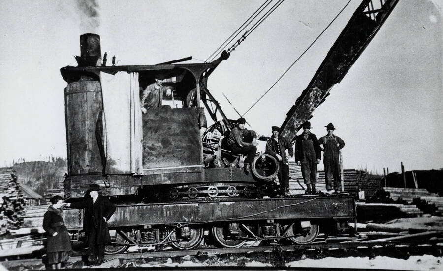 Loading logs near Bovill, Idaho. In the loader is Bill Melon. On the loader, left to right: Fred Wahler, Rosie Wandke, Henry Heidke, unidentified. Standing below, left to right: Betty Helmer, Leo Guilfoy.