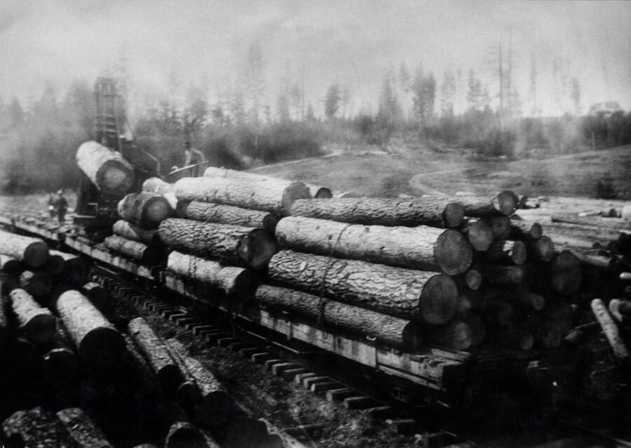 One carload of logs is complete, and the marion tops off the load on one end of the second car. A depression is left at the center of the load, and a chain goes around before the load is finished. The weight of one large or several smaller top logs on the chain keeps it tight and the load secure.