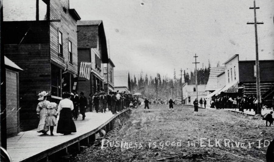 Buildings are identified in book caption: 'Main Street in Elk River about 1913. The first building at left was a rooming house and a cobbler shop. Beyond it (hipped roof) was the Grant and Giles store, and then another rooming house. The other building with the hipped roof is the McDonald store. At right is a dry goods store, the hardware, an unidentified building, and then the Morris Drug.'