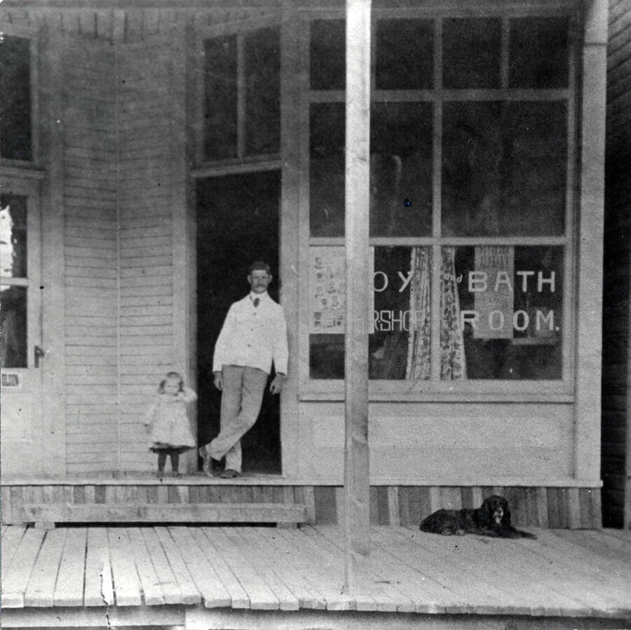 W.S. Miller and his daughter Gladys Miller stand in front of the Troy barbershop and bath room