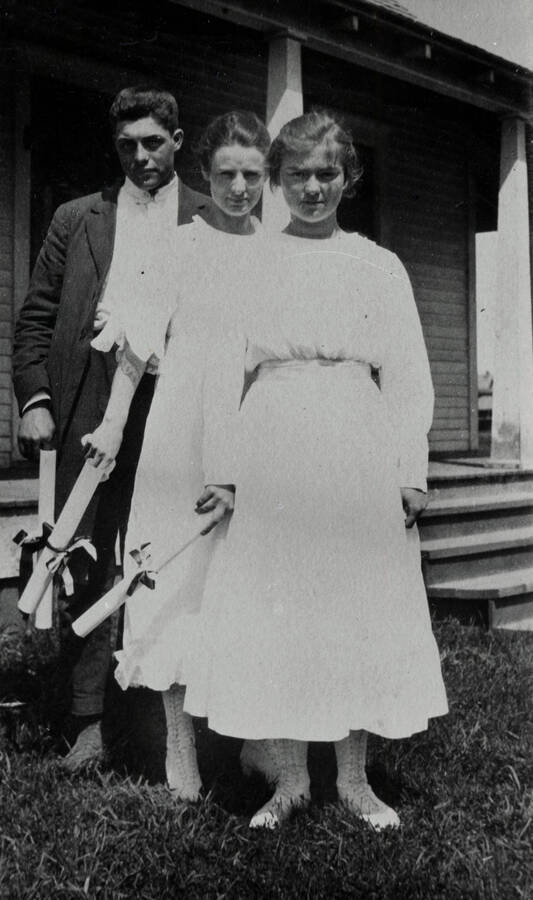Bovill High School's first graduating class. Left to right: Allen Woolsey, Ethel Bellamy, Gladys Miller. Standing in front of Ernie and Nell Wood Smith's house.