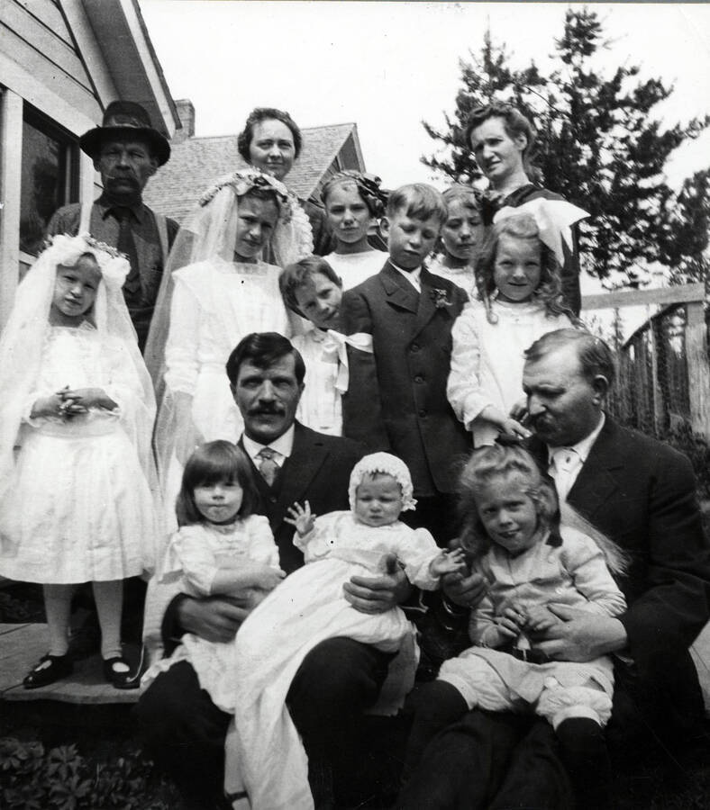 People are identified in caption: 'Back row (adults) Herman Zagelow, Alvina Groh, Mrs. Herman Zagelow. Fourth row, Sophia Zagelow, Marie Zagelow, and two girls not identified. Third row - in dark suit - Johnny Zagelow standing between a boy not identified (left) and Margaret McDonald. in front, John Groh holding Madeleine Groh and Elsie Zagelow, Tom Groh holding his son Tommy.'