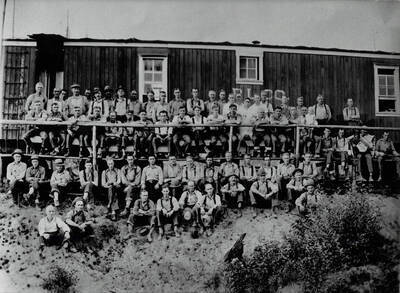 A group of workers at Potlatch Lumber Company's Camp 2 near Elk River, Idaho. Top row (all standing) from left to right: John Donovan, unidentified, Ralph Todd, Gus Peterson, Al Conroy, Gust Anderson, Mike Stepon ('Laughing Mike'), Joe White, Mike Buboly, Benny Campbell, Chuck Schwartz, Oscar Benson, Ed Schwartz, Ed Hilton, Axel Bohn, Ralph Hanson, Socky Hambly, Albert 'Shorty' Justice, unidentified, Charles Mulke, unidentified, Archie Little, Axel Anderson, Joe St. Peter. Second row: unidentified, Henning Sundstrom, Joe Nickoloski, George Ecker, Horace Comstock, Roy Gilbert, Bob Bigham, Jack Wybark, Bill Osborn, Charley Enger, Harold Mael, Mack McCloud, Ralph Wagner, Perry McCloud, Joe Wybark, Fergus Dawson and son Robert, Herb Flodberg, Ben Bates, [?] Thompson and dog, Louie Schultz. Third row: Ed Kellom, Mickey Adams, John McDonald, Gene Bacon, 'Red' Burquist, Leo Benson, Steve Plisko, Charles Hickman, Joe Faucher, Willis Olsoh, unidentified, unidentified, unidentified, Frank Rodgers. Fourth row: Wolfred Olson, Les Wolheter, Fred Fuger, Lawrence Benson, Thomas Nichols, unidentified, John Buckbee, Sam Ryan, Jack Starkey, unidentified.