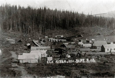 Book caption: 'This is how Elk River looked in September, 1910. Clustered at the center are the log buildings which include the Trumbull homestead and (its roof visible over the homestead cabins) a store. In the Foreground are tents; toward the rear a line of Company houses; at the right, Potlatch Company Headquarters, the mess hall, and the railroad.'