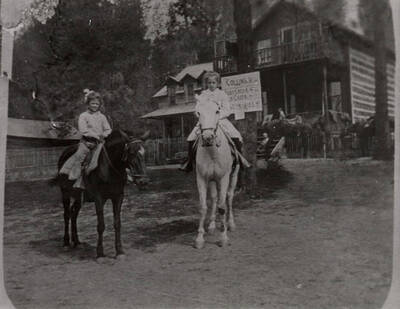 Two young girls sit on horseback in front of the Bovill Hotel. The girl on the left is thought to be Dorothy Bovill, and the girl on the right is thought to be Gwendolyn Bovill.