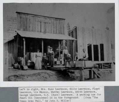 Left to right: Mrs. Russ Lawrence, Ellis Lawrence, Floyd Lawrence, Liz Manson, Warren Lawrence, Edith Lawrence, George Lawrence, G.B. (Russ) Lawrence. A packing box for Pearl Oil (kerosene) is in the foreground.