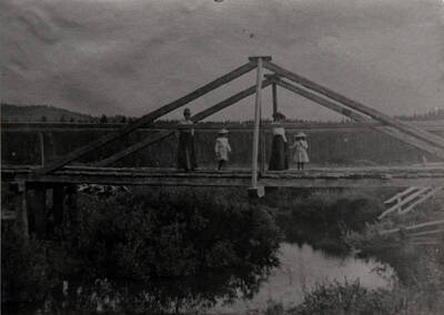 Two women and two children stand on a bridge over the Potlatch River.