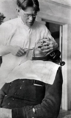 Dr. R.T. Witty extracting a tooth from Tony Peterson.