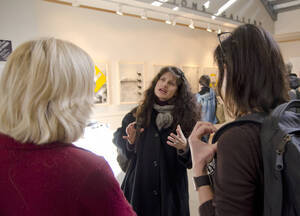 Photograph  15 of Sally Graves Machlis and Delphine Keim-Campbell's Colloquium Talk and Gallery Exhibition 'Road Stories.'  Sally Graves Machlis is Chair and Professor of Art and Design. Dephine Keim-Campbell is Associate Professor of Art and Design. Pictured: Graduate student Lojo Simon talks to Machlis and Keim-Campbell.