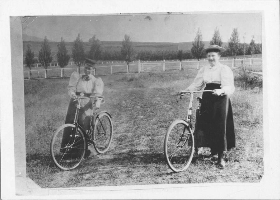 Stella Zononia Hattabaugh with Carrie Mitchell, both with bicycles. Caption reads: 'Left: Carrie Mitchell, Right: Stella Zononia Hattabaugh, Daughter of Regent I. C. Hattabaugh.'